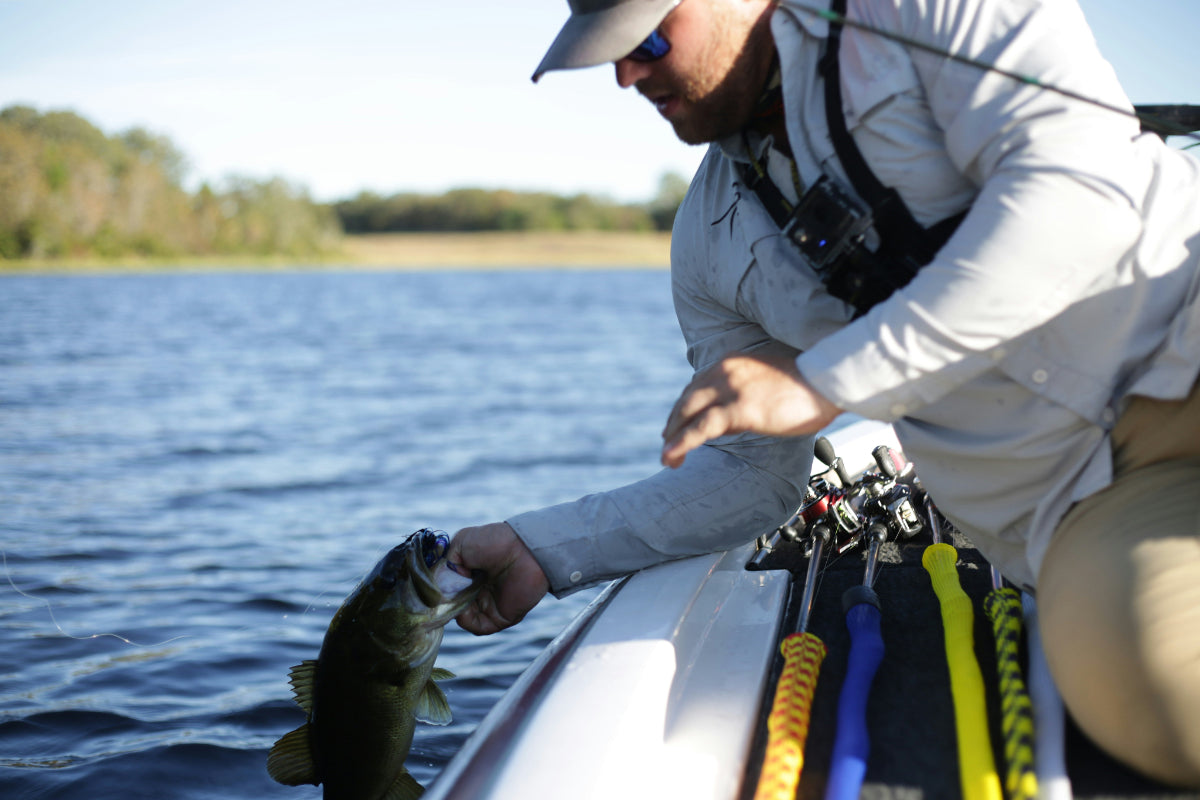 Professional angler catching a largemouth bass with a Pro-Series Laser Minnow jerkbait on a lake boat.